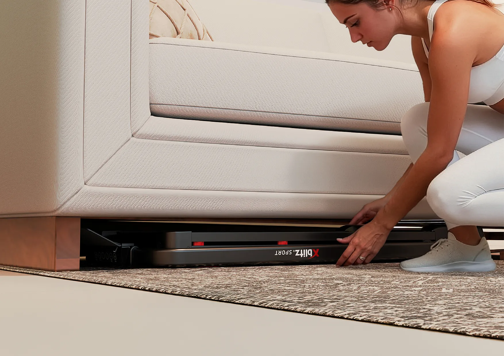 Kobieta wsuwa złożoną bieżnię Xblitz Sport X-Runner 2 pod łóżko w sypialni
